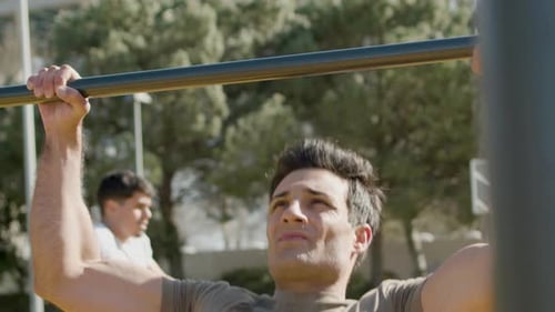 Concentrated Man Doing Pull Up Exercises on Bar Outdoor