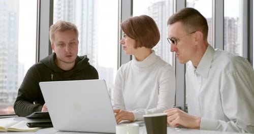 Ein Team von Geschäftsleuten führt bei einem Meeting ein Brainstorming durch und schaut auf den Laptop-Bildschirm.