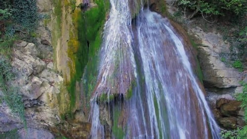 Lush Waterfall Flows Down Mossy Rocks