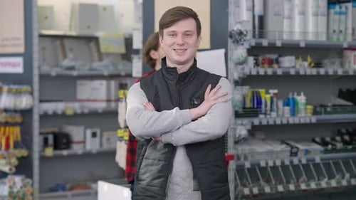 Middle Shot of Young Brunette Man Crossing Hands Looking at Camera Smiling As Male Buyer