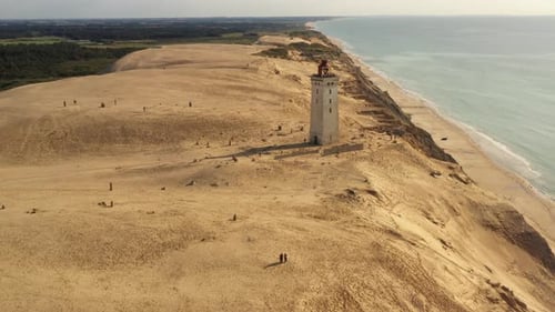 Lighthouse Towering Beside Beach and Ocean From Above