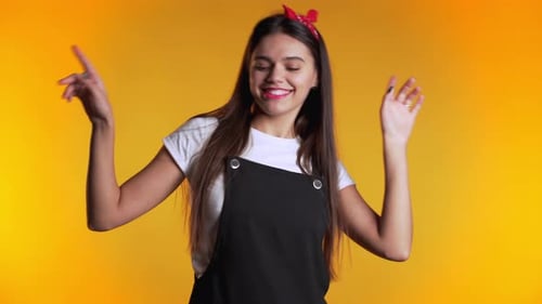 Happy Young Woman Dancing on Yellow Background