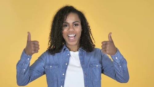 Woman Smiling and Giving Thumbs Up on Yellow