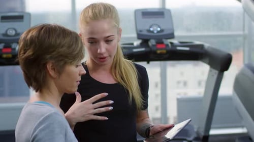 Women Discuss Fitness Plan in Gym