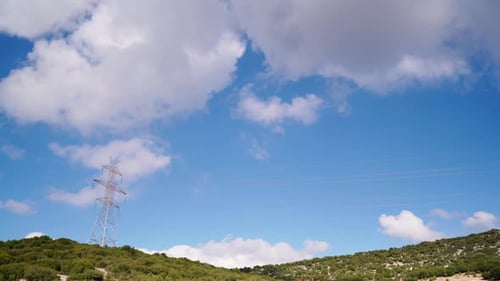 Electrical Tower in Green Landscape with Cloudy Blue Sky