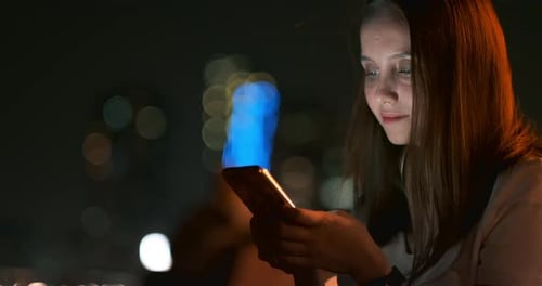 Woman Using Smartphone in City at Night
