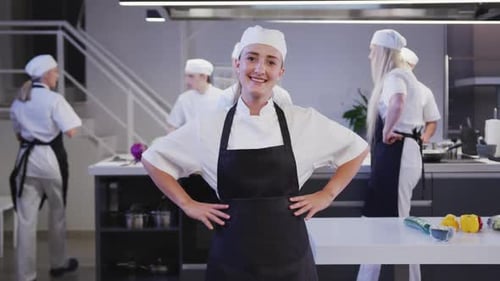Caucasian female cook working in a restaurant kitchen looking at camera and smiling