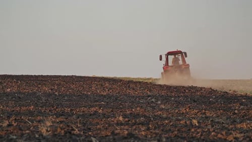 Brown field background and a tractor plowing the soi