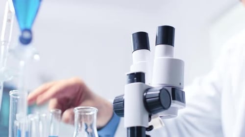 Man Looks Through Microscope in Lab