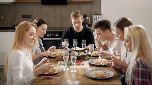Happy Young People Dinning at Table in Kitchen