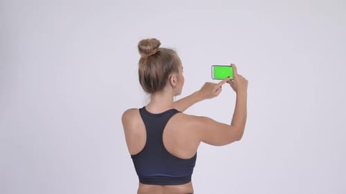 Rear View of Young Blonde Woman Taking Picture with Phone