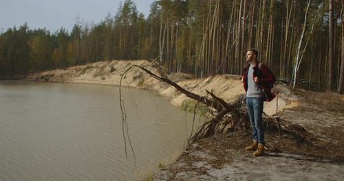 Hiker with a Backpack at Sunset on the Top of a Mountain Enjoying the Sunset with a Raised Hand in a