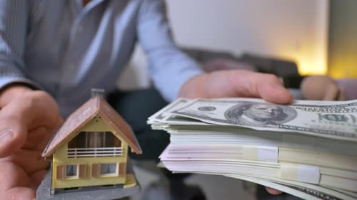 Close up shot of adult man lifts house or money stack at home - consideration of cash money or estat