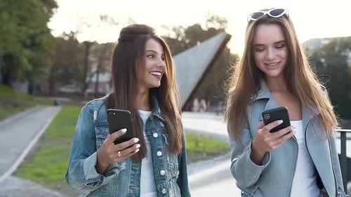 Stylish Women Walk Together Using Smartphones