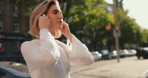 Woman Wearing Wireless Earbuds Walking in a Summer City Slow Motion
