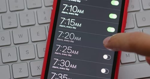 Hand Activating Alarms on Mobile Phone Close Up