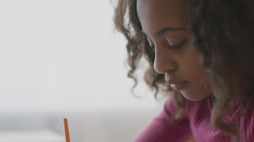 Focused Girl Writes at Table in Bright Daylight