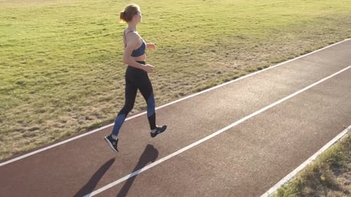 Young Woman Running on Stadium Run Track Outdoors