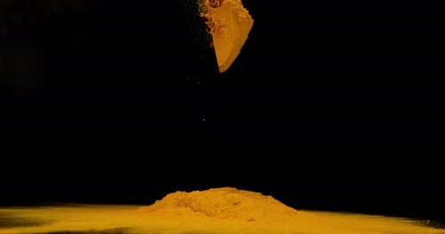 Cúrcuma, cúrcuma longa, polvo que cae sobre fondo negro, especias indias, cámara lenta 4K