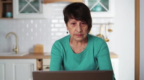 Senior Woman Using Laptop in Bright Kitchen