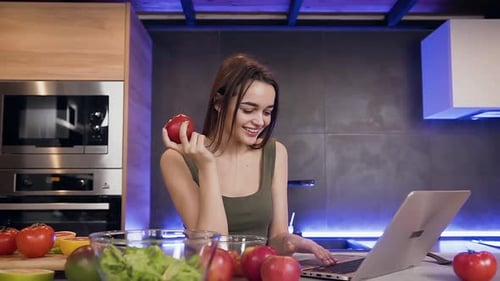 Woman Using Laptop in Modern Kitchen with Salad