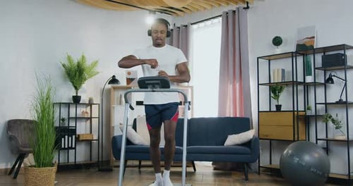 Young Adult Walks on Treadmill in Modern Home Gym