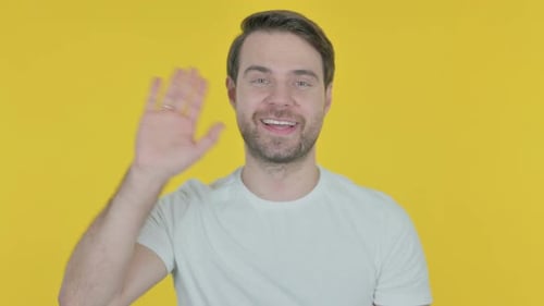 Junger Mann winkt Hand, um Hallo zu sagen auf gelbem Hintergrund
