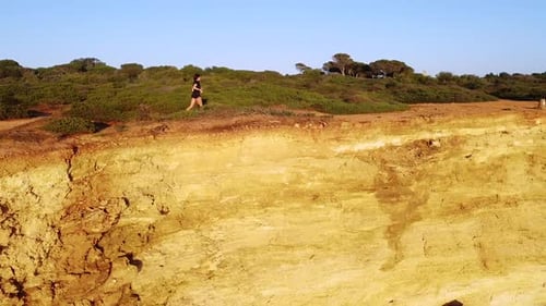 Woman Runs Along Dramatic Coastline at Sunrise