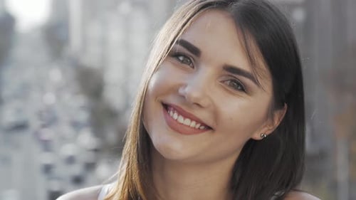 Lovely Young Happy Woman Smiling To the Camera with City Streets on Background