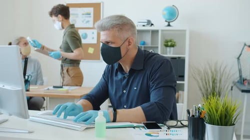 Woman Taking Temperature of Business People Working in Office During Corona Virus Outbreak