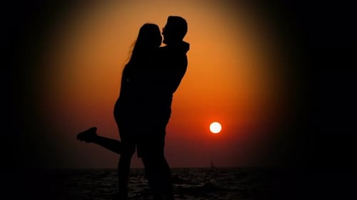 Romantic Couple Silhouette Embracing at Sunset on Beach