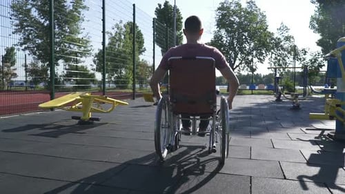 Man Exercising in Wheelchair at Outdoor Workout Park