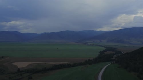 Agriculture and green fields in valley of Altai under thunderstorm sky