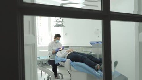 Dentist Performing Dental Procedure on Patient in Office