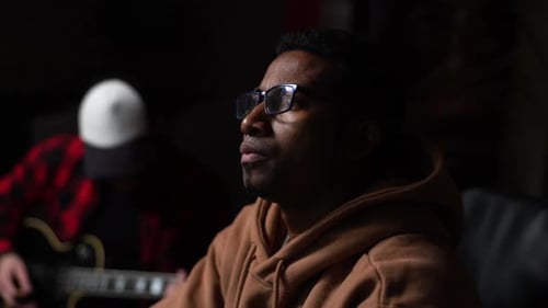 Closeup View of Serious AfroAmerican Sound Producer Working in Recording Studio with Computer