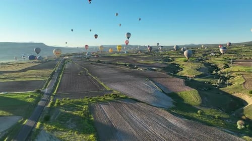 Hot air balloons fly over the mountainous landscape of Cappadocia, Turkey.