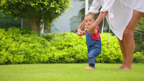 Baby Taking First Steps on Green Lawn