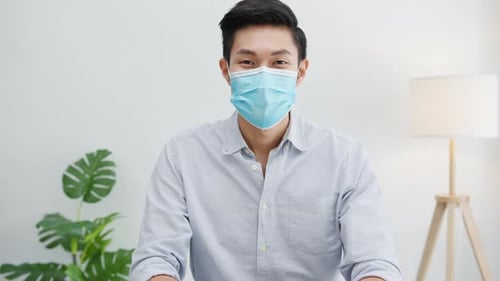 Asian businessman social distancing in situation for virus prevention smiling under mask in office.