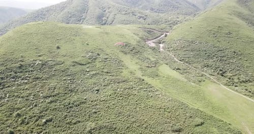 Paraglider Flying Above Green Rolling Hills
