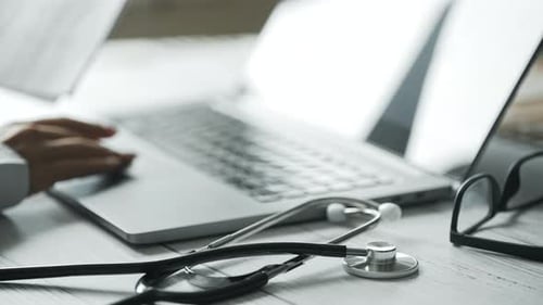 Close Up of a Doctor is Working and Typing on Laptop in a Clinic