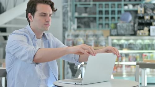 Junger Mann schließt Laptop und geht im Café weg
