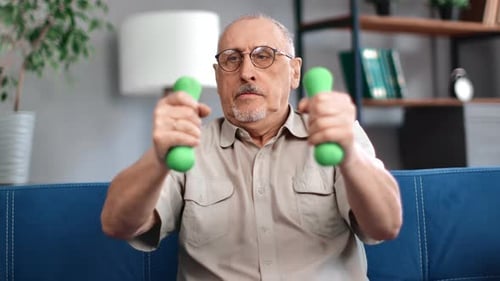 Senior Man Exercising with Dumbbells on Couch