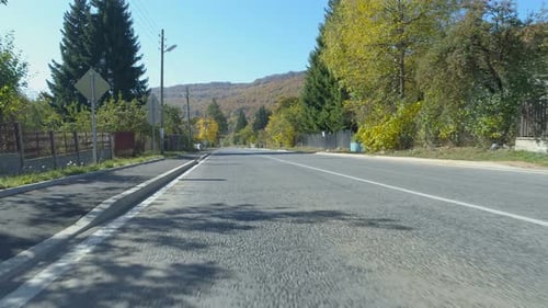 Drone Following White Road Markings in Small Village in Sunny Day