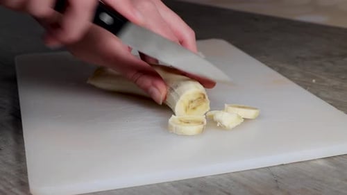 Person Slicing a Banana on a Cutting Board
