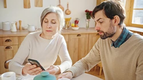 Adult Son and Senior Mother Talking in Kitchen