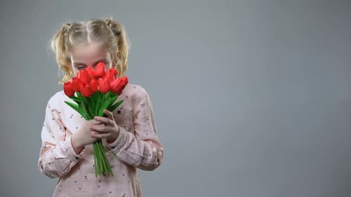 Little Girl Hugging Red Tulips Smiling in Studio