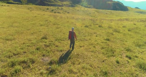 Flight Over Backpack Hiking Tourist Walking Across Green Mountain Field
