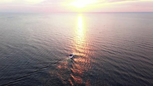 Aerial Sunset Shot of Yacht Sailing During Sunset with Red and Orange Sky Above Reflecting Sea