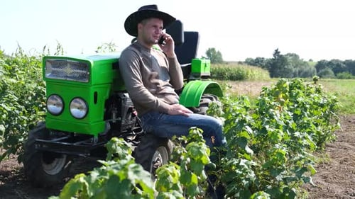Farmer Talking on Cell Phone While Sitting on Tractor