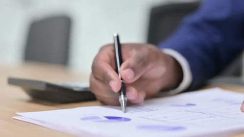 Hand Writes on Financial Documents in Office Setting